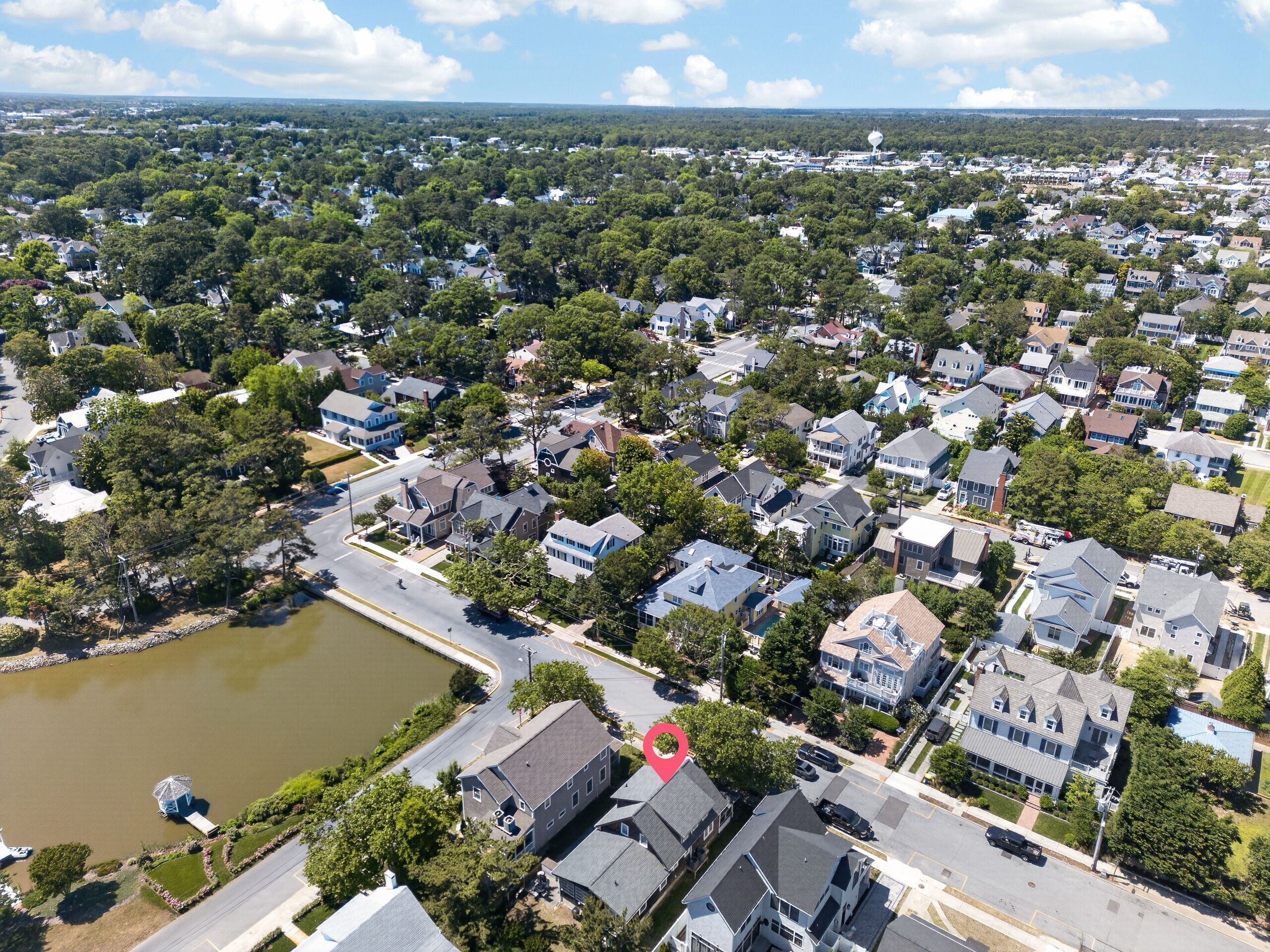 An aerial view of a residential area with houses, a body of water, and a red location marker.