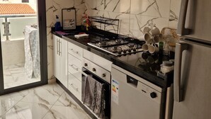 Una cuina moderna amb armaris blancs, un frigorífic d'acer inoxidable i una placa de gas.