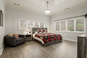 Relax in a spacious bedroom with a large bed, gray walls, and a wooden floor.