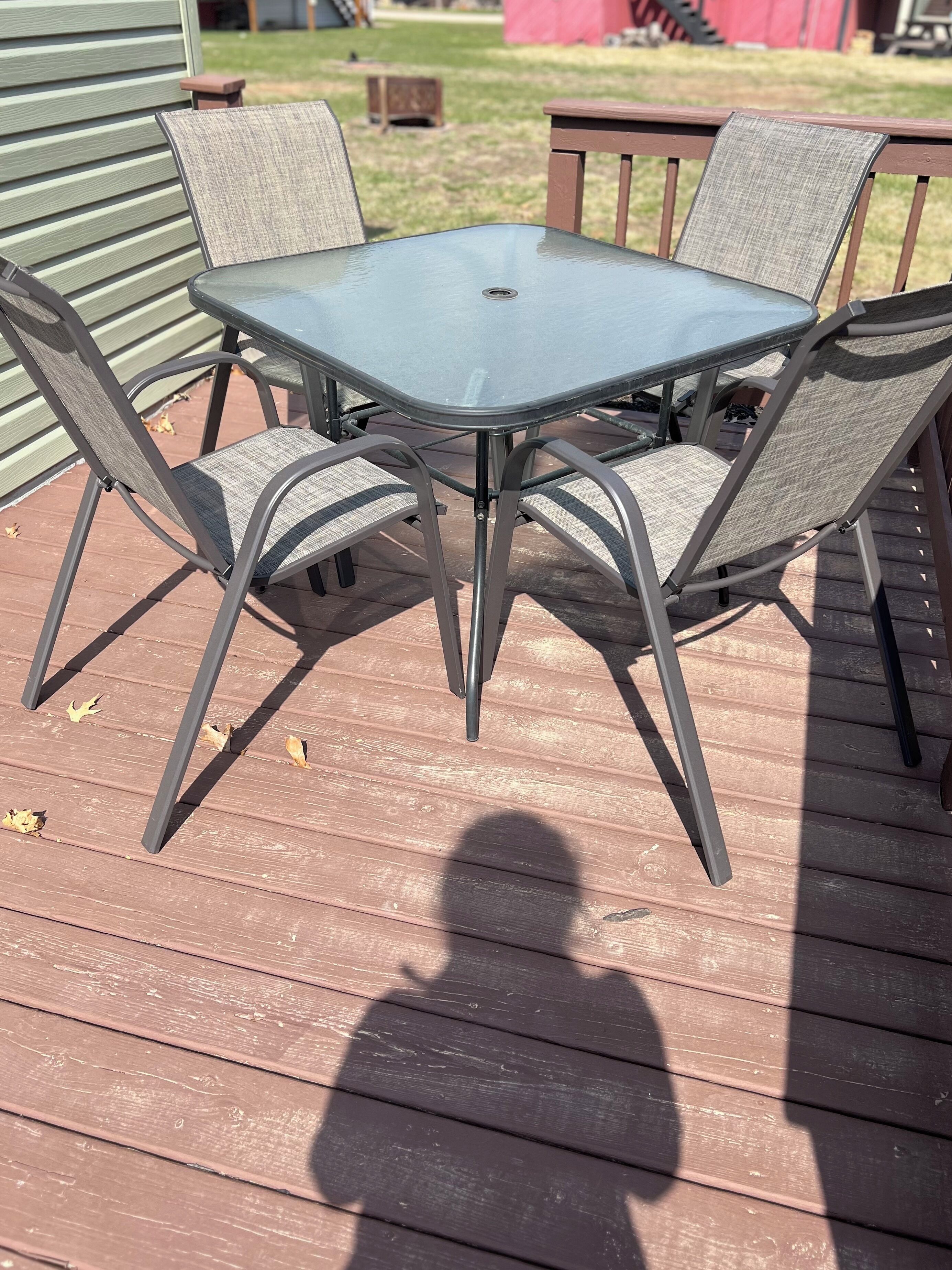 A metal table with four chairs on a wooden deck.