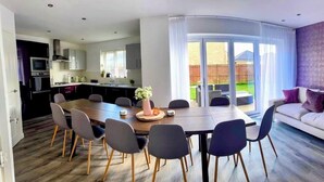 A modern kitchen with a dining area, a sofa, and a view of the backyard. - Elysian Escape, modern 5 bedroom house, sleeps 12 (Darlington)