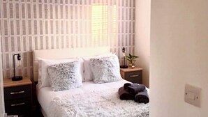 A neatly arranged bedroom with a bed, bedside tables, and a lamp. - Elysian Escape, modern 5 bedroom house, sleeps 12 (Darlington)