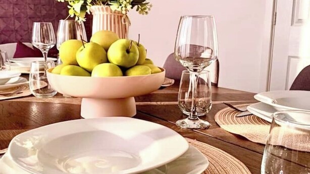 A dining table set with a bowl of green apples, wine glasses, and plates. - Elysian Escape, modern 5 bedroom house, sleeps 12 (Darlington)