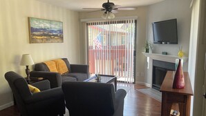 Un salon comprenant un canapé, des fauteuils, une table basse, un téléviseur et une cheminée.