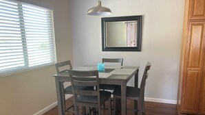Un coin repas comprenant une table et quatre chaises, un luminaire suspendu et un miroir fixé au mur.