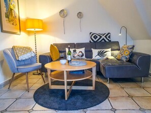 Una sala de estar con sofá, sillones, una mesa de centro y una lámpara.