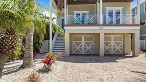 A two-story house with a covered front porch, a garage, and a driveway. - Nautical Tides: 3 Blocks to Beach! Pool Spa! Rooftop Deck by Anna Maria Life Vacation Rentals (Bradenton Beach)