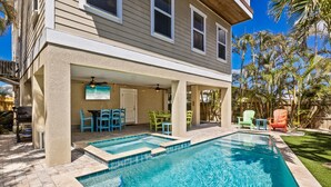 A house with a swimming pool, outdoor seating, and a covered patio area. - Nautical Tides: 3 Blocks to Beach! Pool Spa! Rooftop Deck by Anna Maria Life Vacation Rentals (Bradenton Beach)