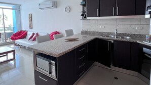 Une cuisine moderne avec des meubles de couleur sombre, un plan de travail en granit et un four à micro-ondes encastré.