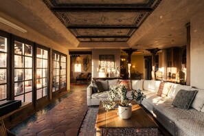 A spacious living room with a large sofa, a coffee table with a plant, and a patterned rug.