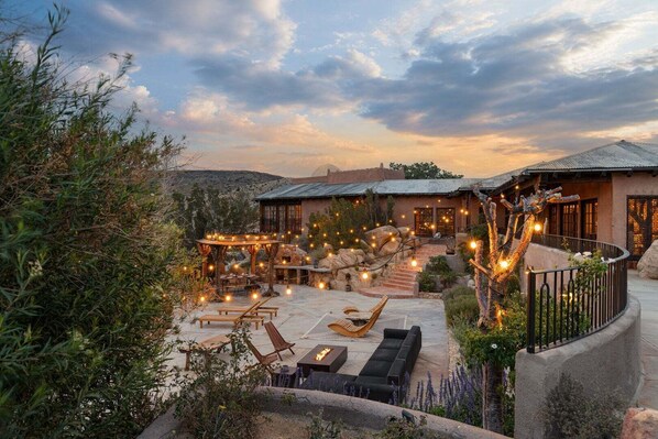 A resort with outdoor seating, a fire pit, and string lights.