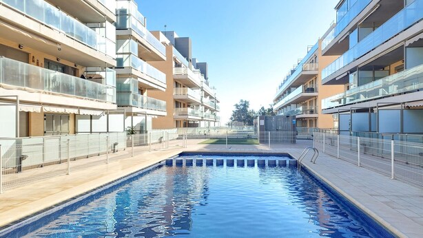A swimming pool surrounded by modern apartment buildings with balconies.