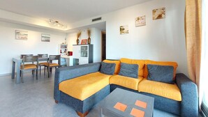 A modern living room with a sectional sofa, a dining area, and a small table.