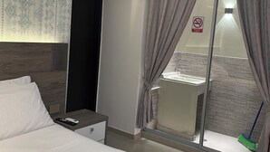 A hotel room with a bed, a nightstand, an air conditioning unit, a bathroom with a sink and a shower, and a view of the outside through a glass door. - Luxury Liv Limonar (Cali)