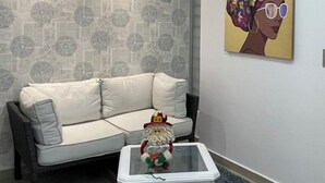 A modern living room with a white sofa, a glass coffee table, and a wall with a patterned wallpaper. - Luxury Liv Limonar (Cali)