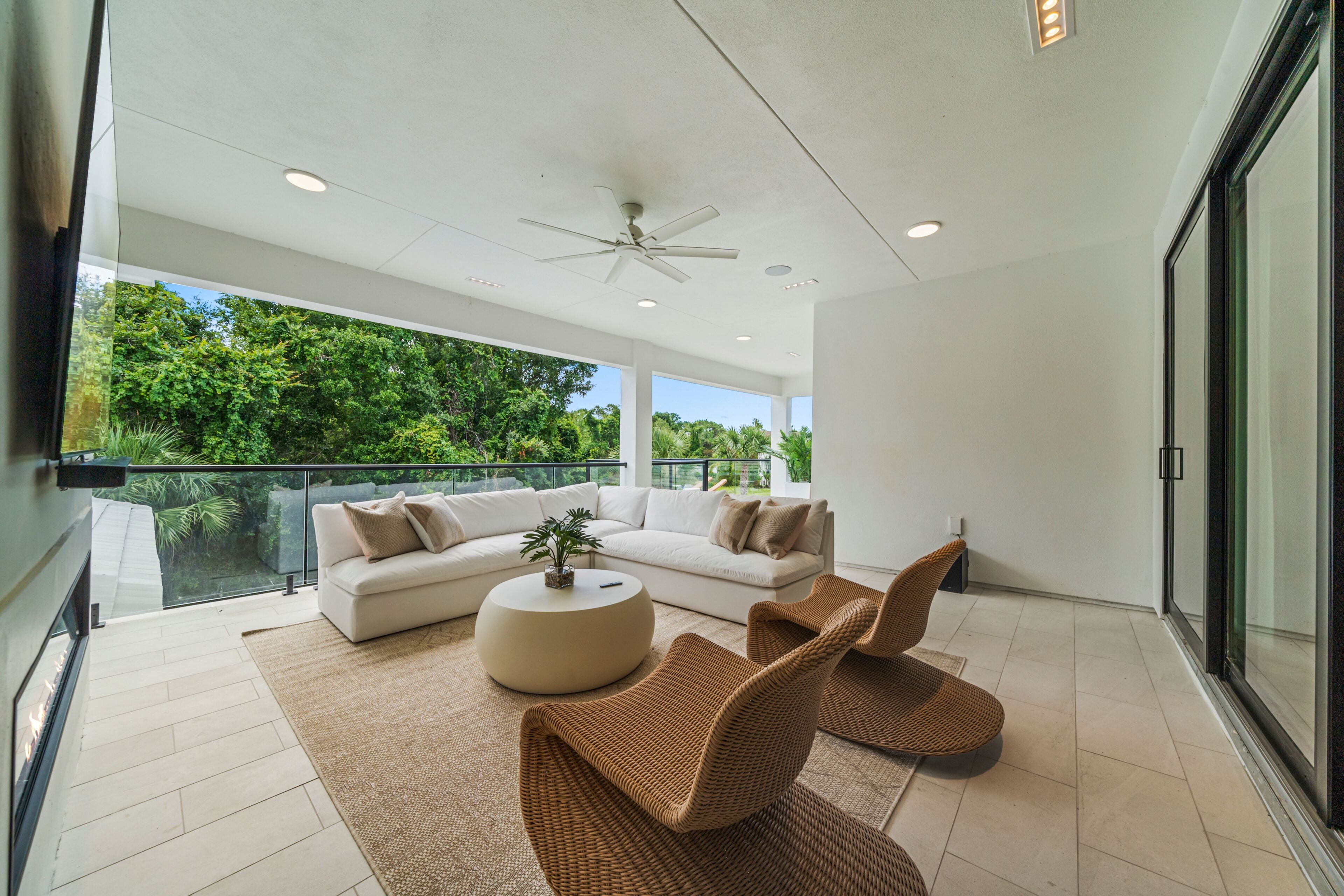 A modern living room with a white sofa, a round coffee table, and wicker chairs.
