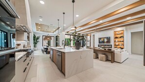 A spacious kitchen with a central island, modern pendant lighting, and a dining area with a sofa and coffee table. - The Palm House at Reunion-TT484 (Kissimmee)