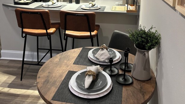 Una cocina moderna con una isla central, electrodomésticos de acero inoxidable y un comedor con una mesa redonda y sillas.