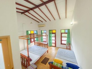 A dormitory room with bunk beds, a desk, and a chair. There are windows with curtains and a door. - Summer Lodge (Tangalle)