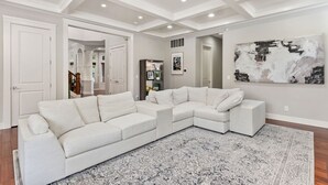 A spacious living room with a large L-shaped sectional sofa, a patterned rug, and a modern abstract painting on the wall. - Luxury Lake Waterfront Friendly Retreat (Federal Way)
