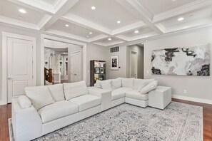 A spacious living room with a large L-shaped sectional sofa, a patterned rug, and a modern abstract painting on the wall. - Luxury Lake Waterfront Friendly Retreat (Federal Way)
