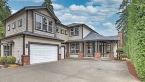 A two-story house with a garage, a covered entryway, and a well-maintained driveway. - Luxury Lake Waterfront Friendly Retreat (Federal Way)