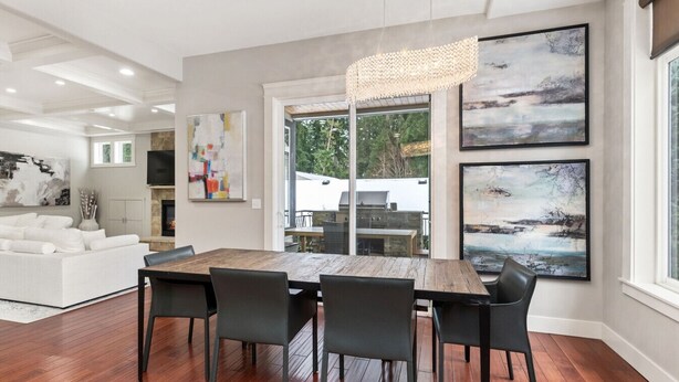 A modern dining area with a wooden table and chairs, a fireplace, and large abstract paintings on the walls. - Luxury Lake Waterfront Friendly Retreat (Federal Way)