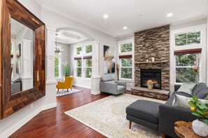 A spacious living room with hardwood floors, a fireplace, and large windows.