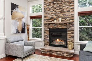 A living room with a stone fireplace, grey sofas, and a large abstract painting.