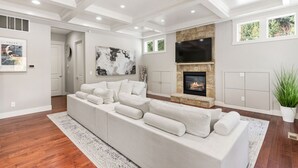 A modern living room with a sectional sofa, a fireplace, and a large TV. - Luxury Lake Waterfront Friendly Retreat (Federal Way)