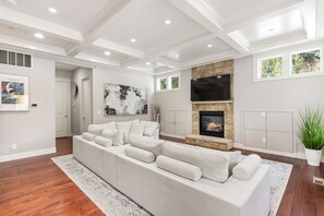 A modern living room with a sectional sofa, a fireplace, and a large TV. - Luxury Lake Waterfront Friendly Retreat (Federal Way)