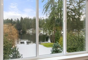 A view from a window overlooking a lake with dock, trees, and buildings in the background.
