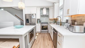 A modern kitchen with white cabinetry, stainless steel appliances, and a wooden floor. - Oceanside, ELEV, Priv Pool, Comm Amenities, Dogs Welcome-BH7, O'Buoy (Corolla)