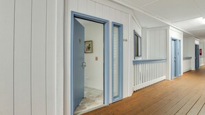 Un couloir aux murs blancs et aux moulures bleues, doté d’un plancher en bois et de portes numérotées A-129 et A-130.
