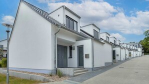 Eine Reihe moderner, weißer Gebäude mit flachen Dächern, einem gepflasterten Weg und blauem Himmel.