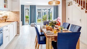 Eine moderne Küche mit Essbereich, einem Holztisch, blauen Stühlen und einer Treppe.