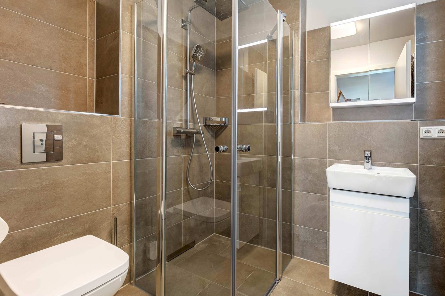 Une salle de bain moderne avec une douche à parois de verre, un lavabo blanc et des toilettes.
