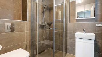 Une salle de bain moderne avec une douche à parois de verre, un lavabo blanc et des toilettes.