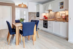Une cuisine moderne avec des meubles blancs, une table à manger en bois et des chaises bleues.
