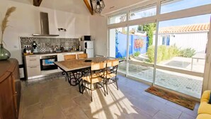A kitchen with a tiled backsplash, a stove, and a dining area with wicker chairs. - The Fleur de Sel - 6 people (Les Sables-d´Olonne)