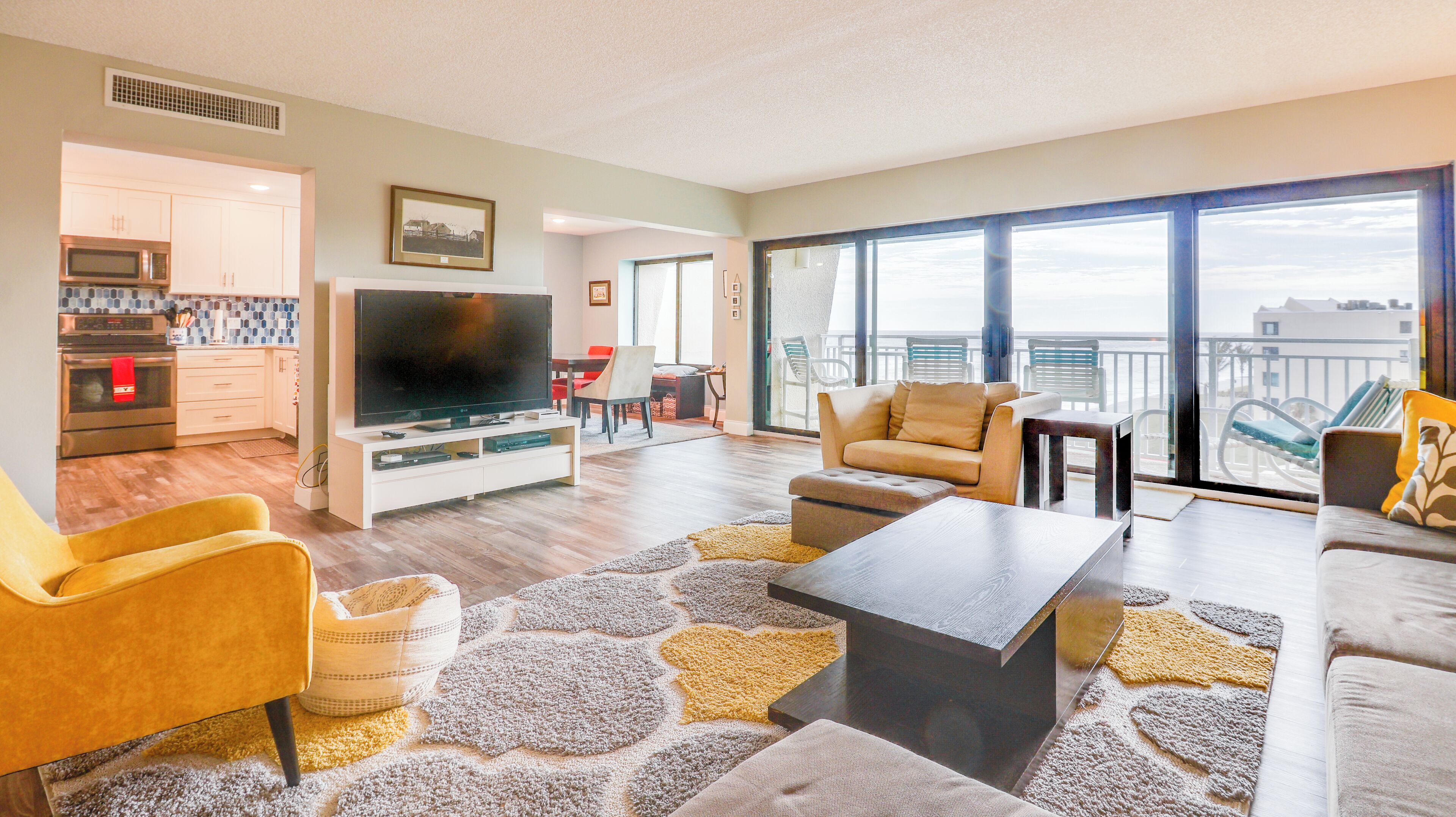 Ein modernes Wohnzimmer mit Flachbildfernseher, bequemen Sitzgelegenheiten, Essbereich und einem Balkon mit Blick.
