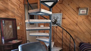 A room with a spiral staircase, a leather armchair, and a small table with a remote control. - Cozy 4-bedroom cabin with AC, fitness room, WiFi in fantastic Modoc (Modoc)