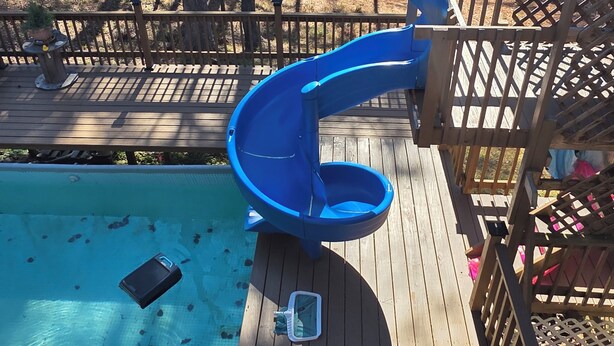 A wooden deck with a blue slide, a pool, and a wooden fence. - Cozy 4-bedroom cabin with AC, fitness room, WiFi in fantastic Modoc (Modoc)