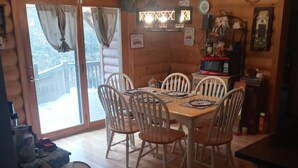 A wooden interior with a dining table and chairs, a trash bin, and a kitchen area with a microwave. - Cozy 4-bedroom cabin with AC, fitness room, WiFi in fantastic Modoc (Modoc)