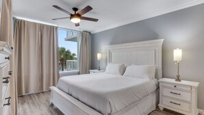 A bedroom with a large bed, a ceiling fan, and a nightstand with a lamp. - ☀️ Pelican 307: Your VIP Beach Getaway Awaits | Lazy River & FREE Golf (Fort Walton Beach)
