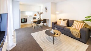 Una sala moderna con un sofá gris, una mesa de centro y un comedor con una mesa y sillas blancas.