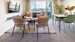 Una sala de estar moderna con un sofá, sillas, una mesa de centro y un televisor montado en la pared.