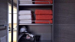 Ein Hotelzimmer mit einer eingebauten Ablage, auf der ordentlich gefaltete Handtücher in Weiß und Rot liegen.