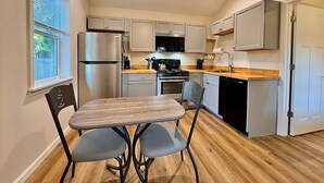 A compact kitchen with a dining table, chairs, a refrigerator, stove, microwave, and cabinets.