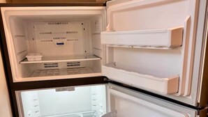 A double-door refrigerator with multiple shelves and compartments, built into a kitchen with wooden cabinets above.